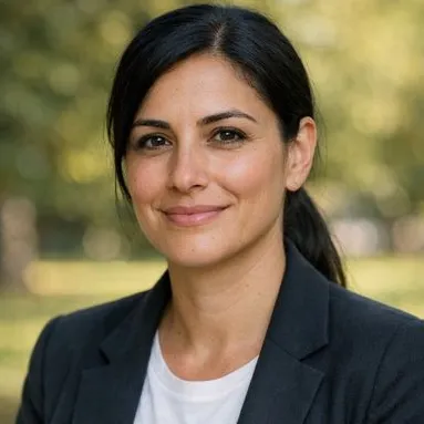 Woman around 37, olive skin, black hair in low ponytail, dark blazer, relaxed expression